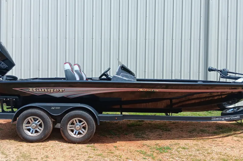 The Image of 2025 Ranger ALPHA 208 boat on trailer, parked outdoors near metal building. - 0