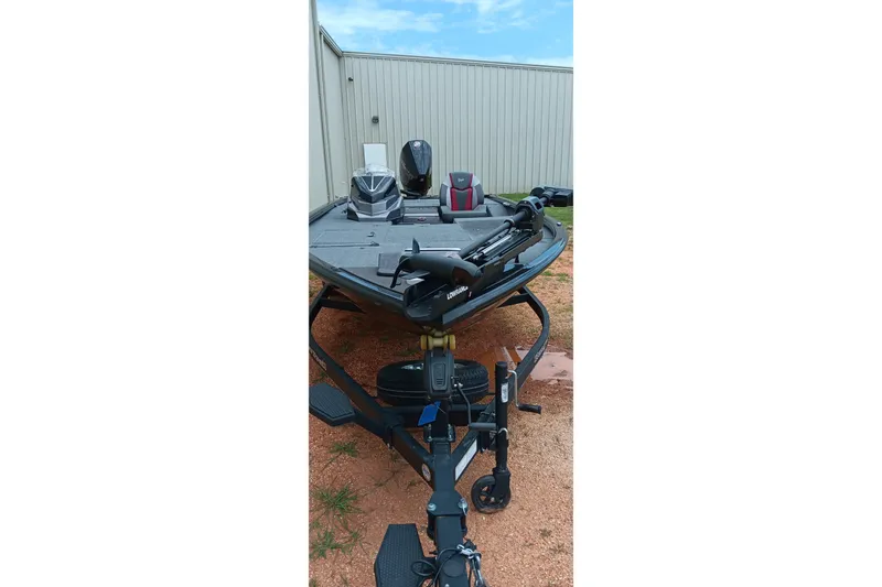 Slide: The Image of 2025 Ranger ALPHA 208 boat on trailer, parked outdoors near a metal building. - 13