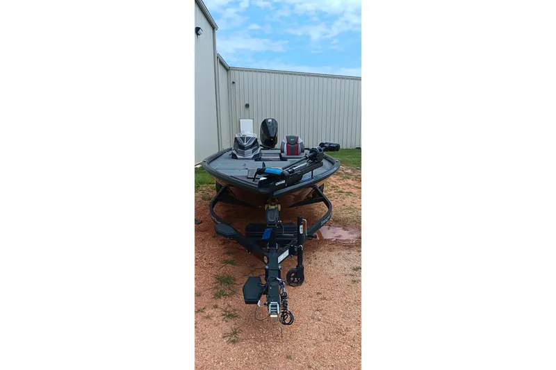 Slide: The Image of 2025 Ranger ALPHA 208 boat on trailer, parked near a metal building. - 12
