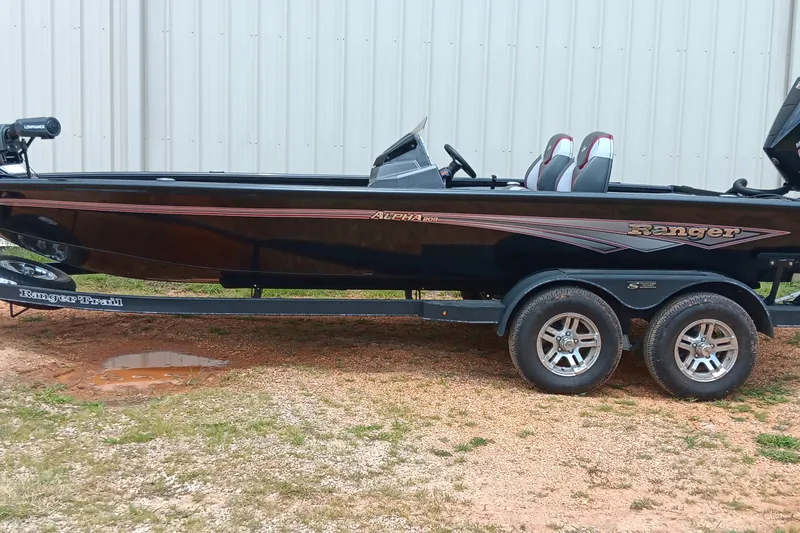 Slide: The Image of 2025 Ranger ALPHA 208 boat on trailer, parked outdoors near a metal building. - 1