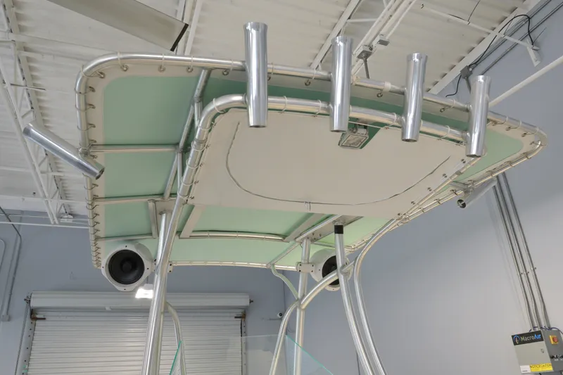 Slide: The Image of T-top of 2014 Sailfish 220 CC boat with rod holders and speakers in a garage. - 6