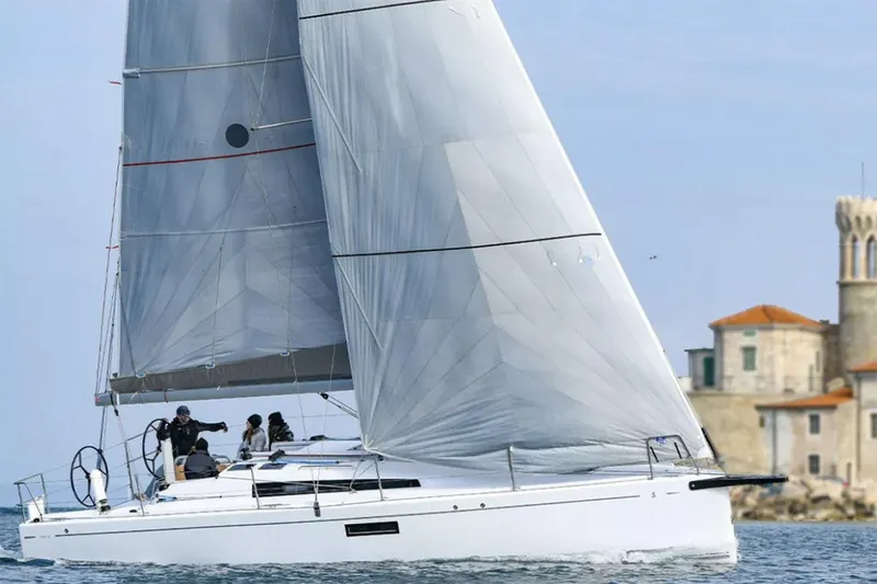 Slide: The Image of Manufacturer Provided Image: 2026 Beneteau First 36 sailboat cruising near a coastal building. - 2