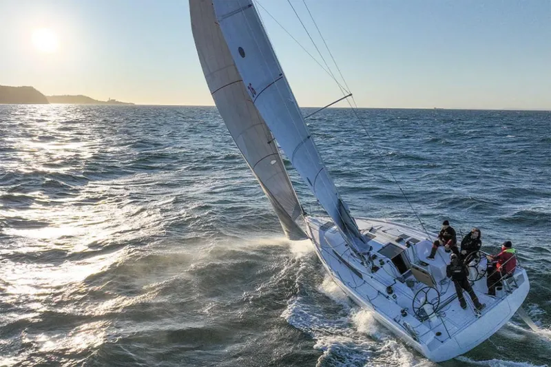 Slide: The Image of Manufacturer Provided Image: 2026 Beneteau First 36 sailing on open sea with crew, under clear sky. - 1