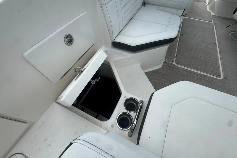 Slide: The Image of 2020 Sea Ray SPX 230 boat interior with open storage compartment and cup holders. - 19