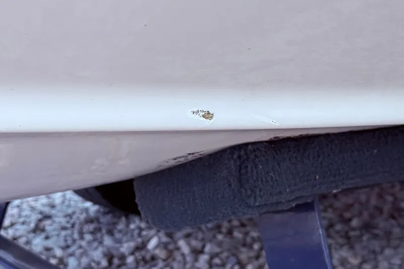 Slide: The Image of 2008 Crownline 220 EX boat hull with visible chip damage on trailer. - 6