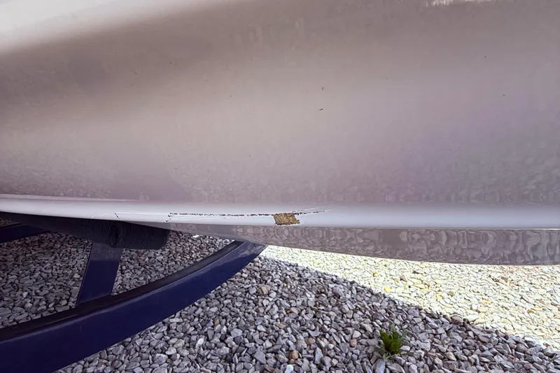 Slide: The Image of 2008 Crownline 220 EX boat hull with visible damage on a gravel surface. - 5