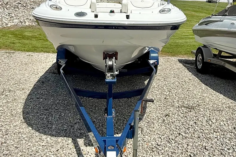 Slide: The Image of 2008 Crownline 220 EX boat on trailer, parked on gravel with grassy background. - 2