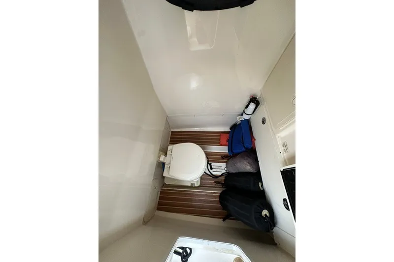 Slide: The Image of Interior of 2016 Scout 255 LXF boat showing compact bathroom with toilet and storage. - 18