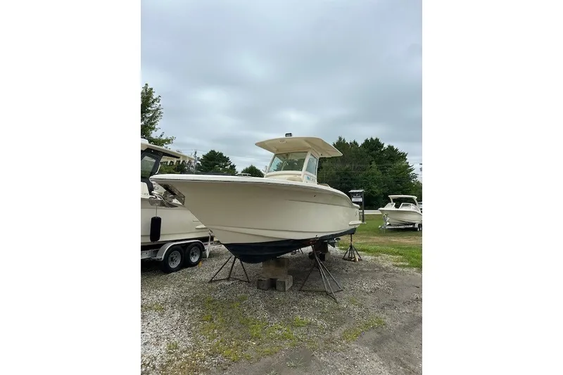 Slide: The Image of 2016 Scout 255 LXF boat on stands, parked outdoors on gravel. - 2