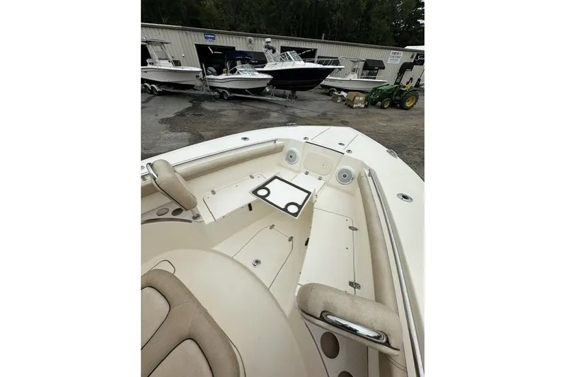 Slide: The Image of 2016 Scout 255 LXF boat interior with seating and cup holders, parked near other boats. - 12