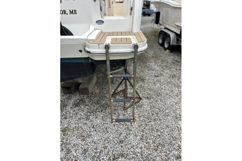 Slide: The Image of 2016 Scout 255 LXF boat with extended swim ladder on gravel surface. - 8