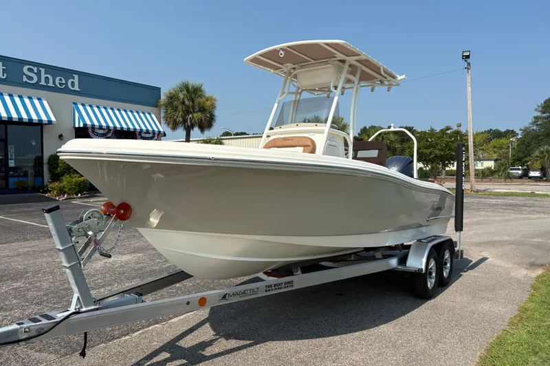 Slide: The Image of 2027 Pioneer 202 Islander boat on trailer outside a store with striped awnings. - 7