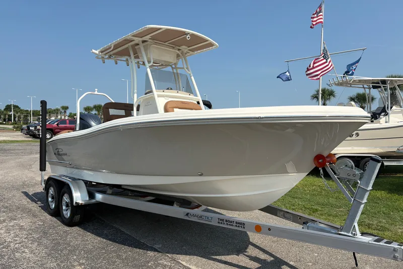 Slide: The Image of 2027 Pioneer 202 Islander boat on trailer, displayed outdoors with flags in the background. - 5