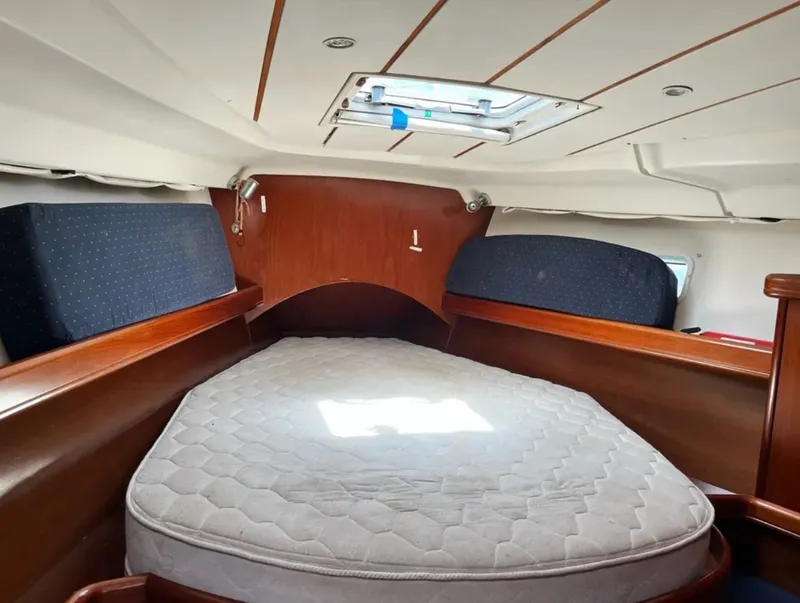 Slide: The Image of The cabin of a 2005 Beneteau 423 with a large bed and wood paneling. - 5