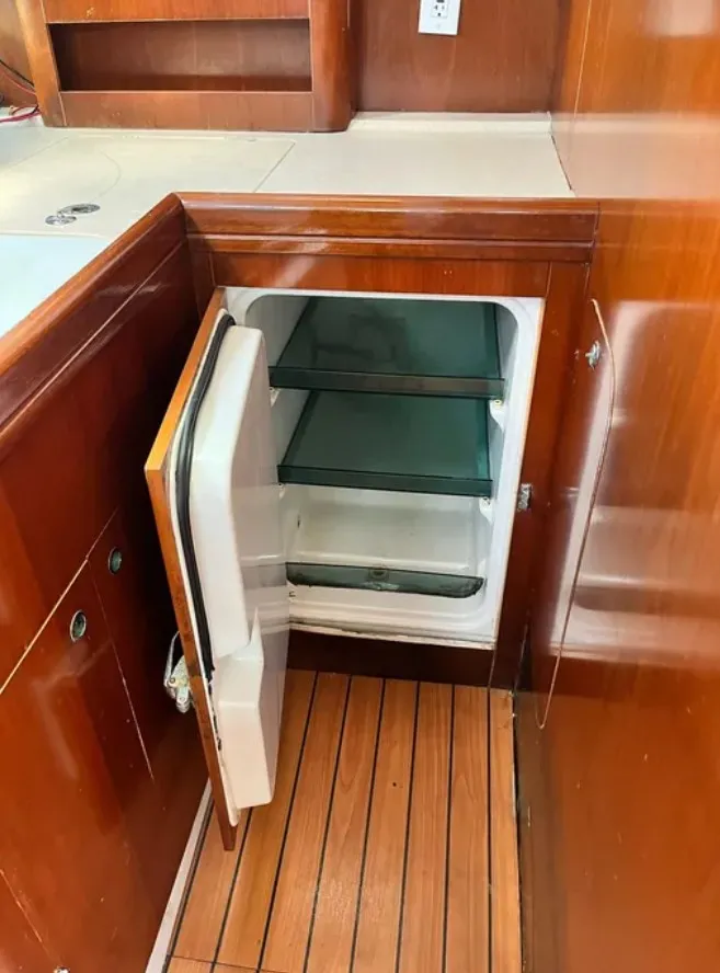Slide: The Image of The interior of a 2005 Beneteau 423 features an open fridge and wooden flooring. - 9