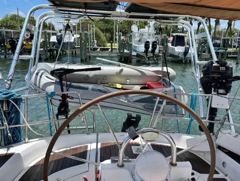 Slide: The Image of The image shows the cockpit of a 2005 Beneteau 423 with a wooden steering wheel and a dinghy in the background. - 4