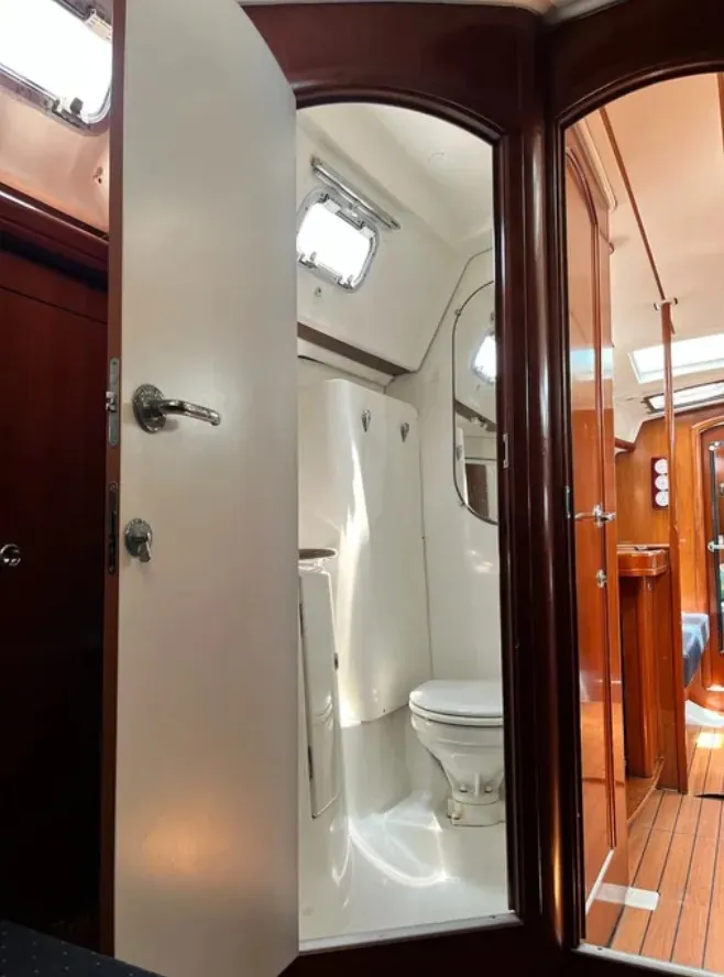 Slide: The Image of The interior of a 2005 Beneteau 423 features a bathroom with a toilet and wood paneling. - 15