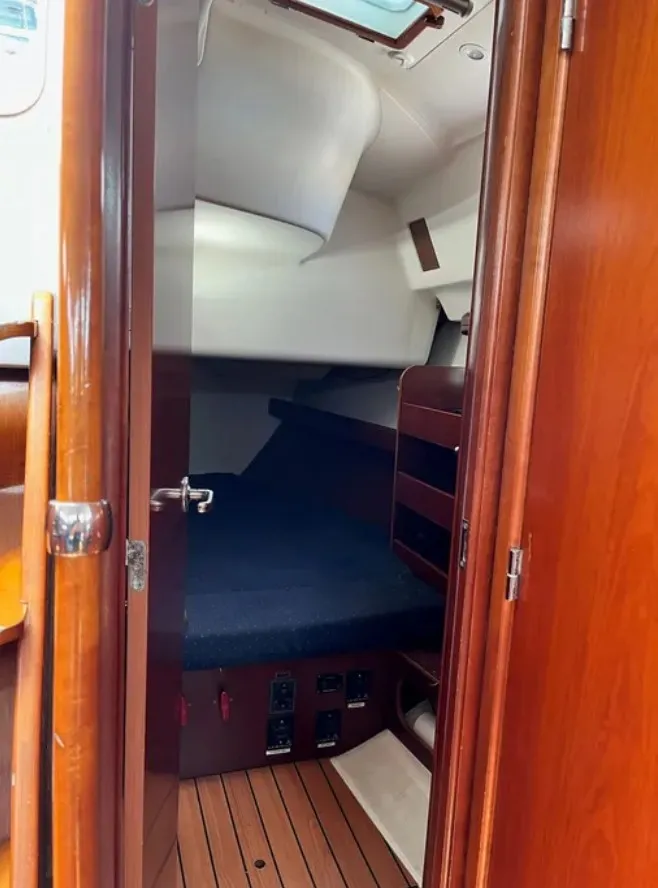 Slide: The Image of The cabin of a 2005 Beneteau 423 with wooden doors and a cozy sleeping area. - 17