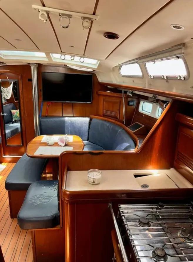 Slide: The Image of The interior of a 2005 Beneteau 423 features a cozy seating area, wooden furnishings, and a galley. - 8