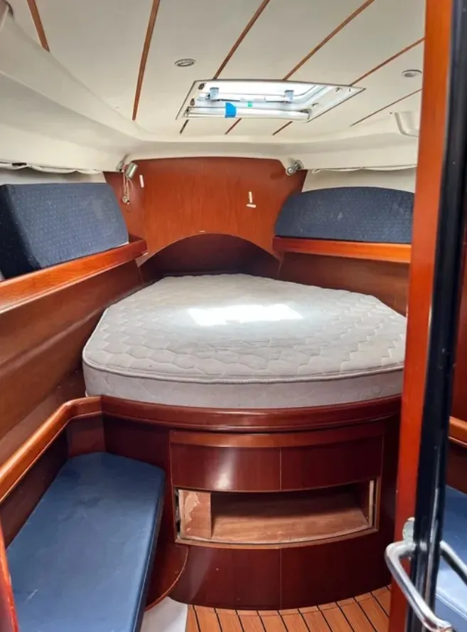 Slide: The Image of The cabin of a 2005 Beneteau 423 featuring a large bed and wooden furnishings. - 7