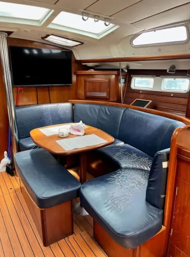 Slide: The Image of The interior of a 2005 Beneteau 423 features a cozy seating area with a wooden table and blue cushions. - 11