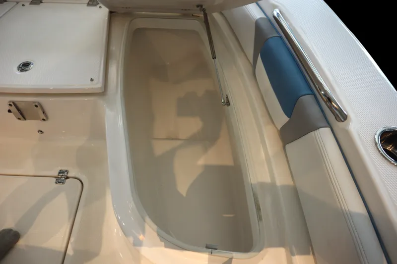 Slide: The Image of 2026 Robalo 226 Cayman boat interior storage compartment with cushioned seating and stainless steel handle. - 10