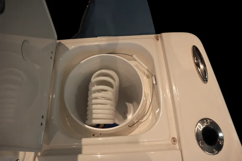 Slide: The Image of Livewell compartment on 2026 Robalo 226 Cayman boat, featuring a coiled hose. - 28