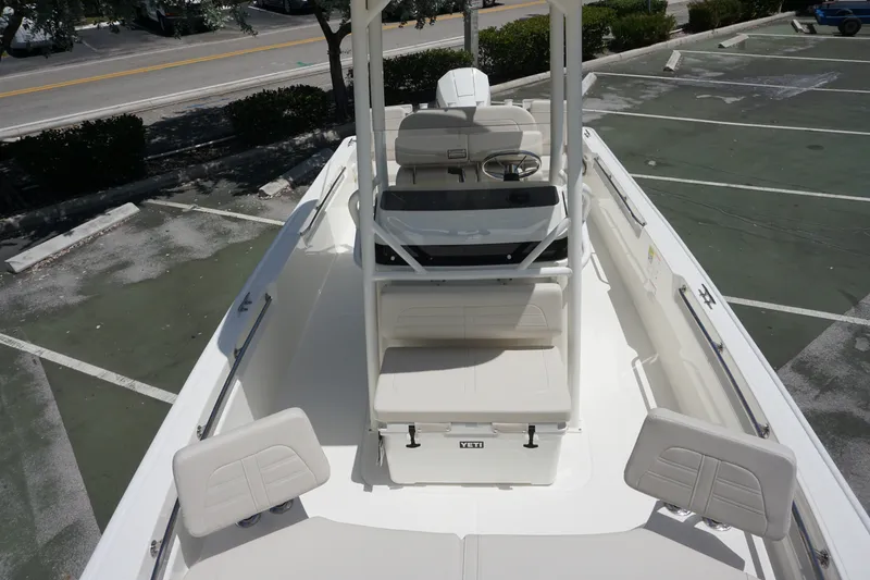 Slide: The Image of 2027 Boston Whaler 210 Montauk boat interior, featuring seating and steering console in a parking lot. - 30