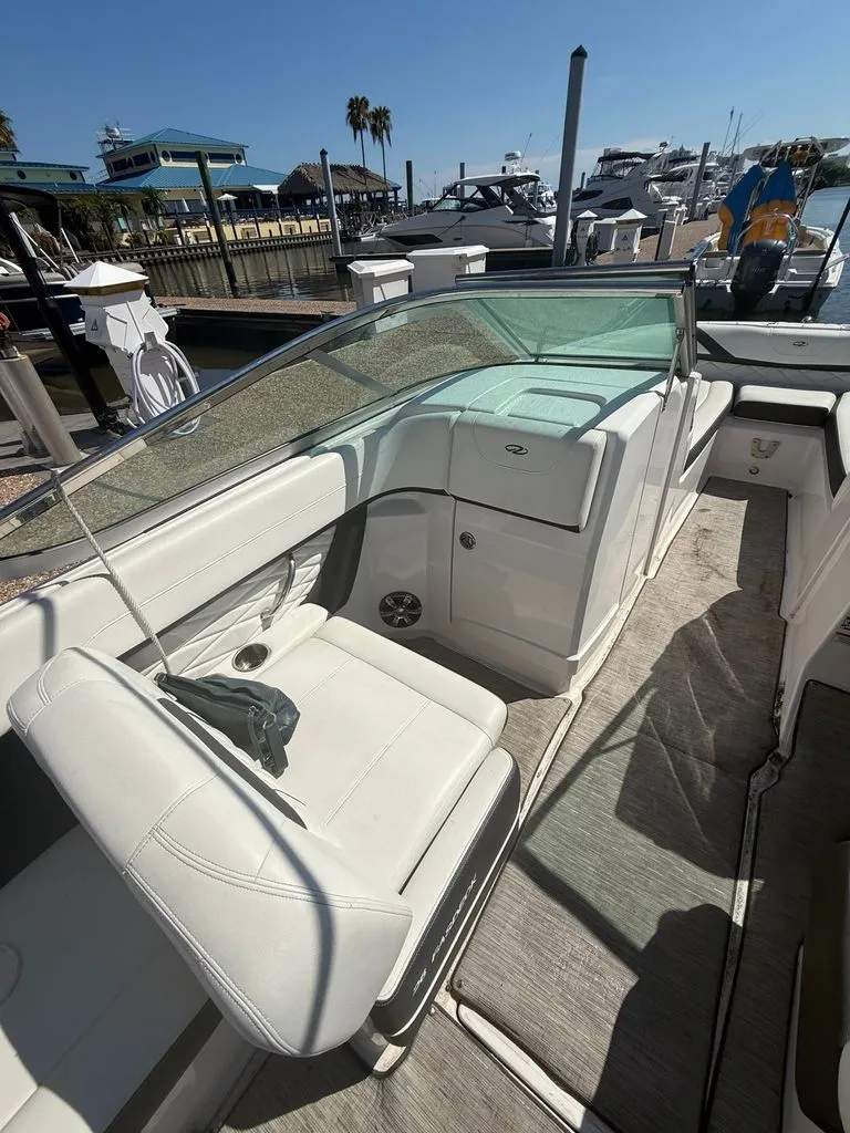 Slide: The Image of The image shows the cockpit of a 2018 Regal 26 FasDeck boat with white seating and a clear glass windshield. - 6