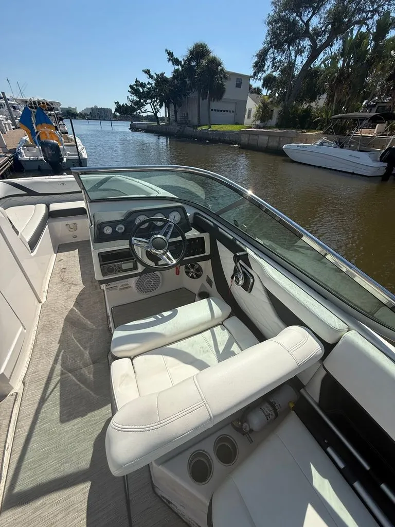 Slide: The Image of 2018 Regal 26 FasDeck: Sleek cockpit with white upholstery, steering wheel, and console, docked by the water. - 5