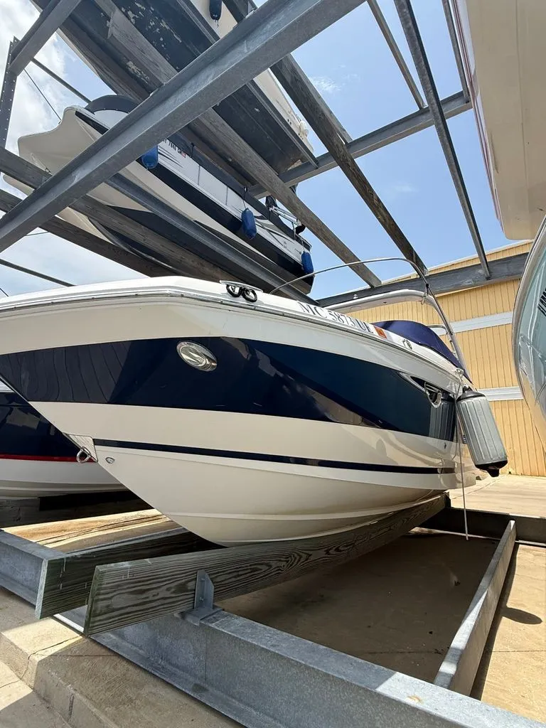 Slide: The Image of A 2018 Regal 26 FasDeck boat stored on a rack, featuring a blue and white exterior. - 7