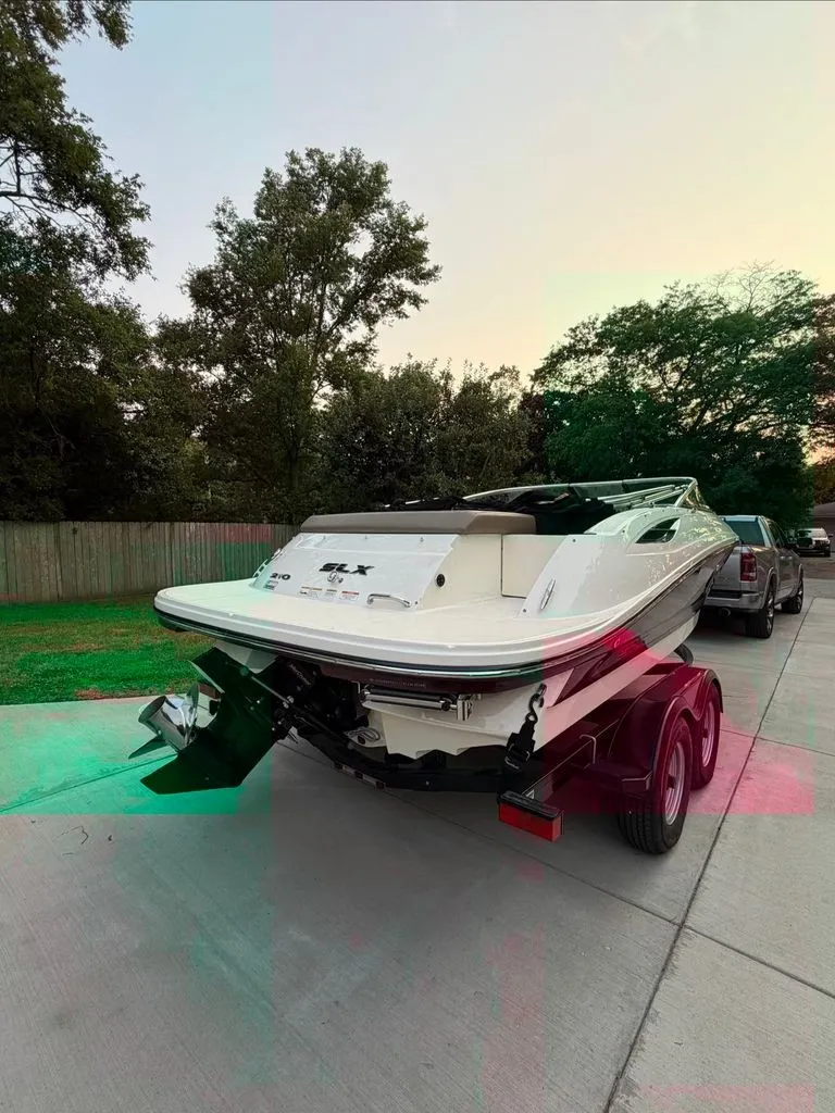 Slide: The Image of A 2013 Sea Ray 210 SLX on a trailer, parked on a driveway next to a car. - 27