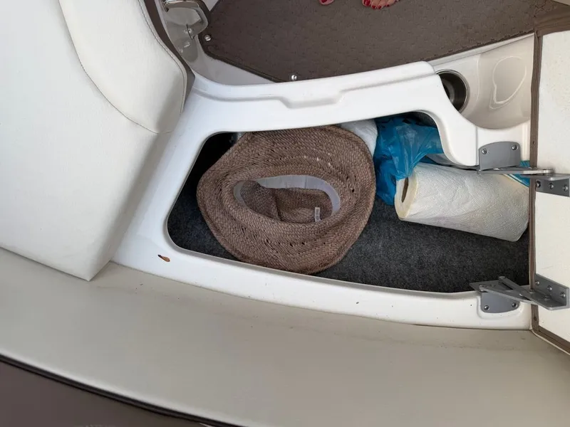 Slide: The Image of A storage compartment in the boat with a hat, paper towel roll, and a blue bag. - 13
