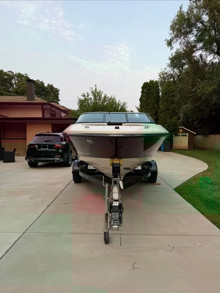 Slide: The Image of A 2013 Sea Ray 210 SLX is on a trailer in a driveway. - 24