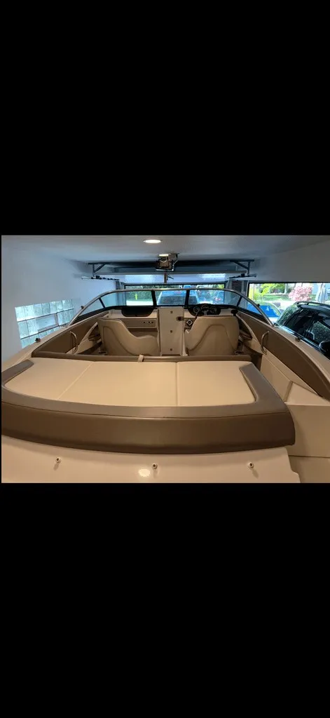Slide: The Image of A 2013 Sea Ray 210 SLX in a garage. It features beige and brown upholstery. - 18