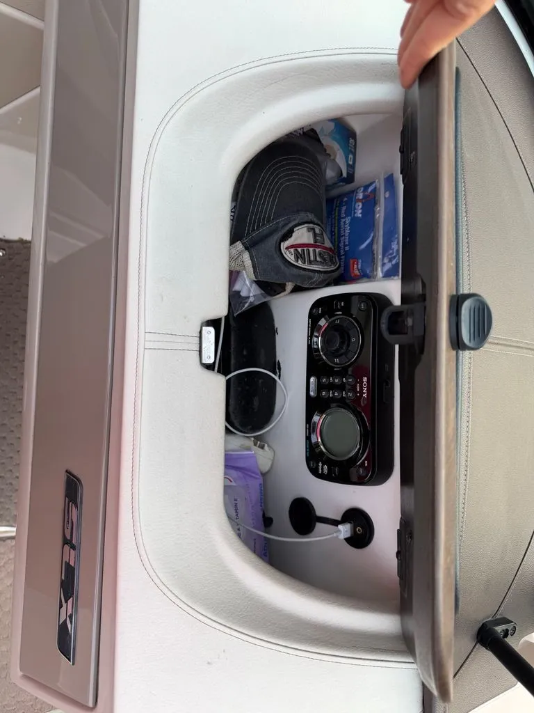 Slide: The Image of A storage compartment in a Sea Ray 210 SLX boat with a cap and a radio. - 15