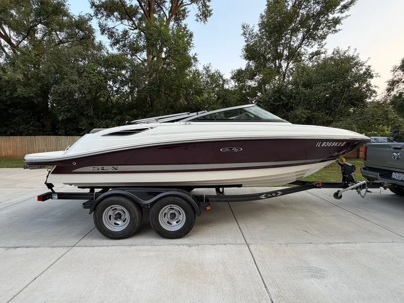 The Image of A 2013 Sea Ray 210 SLX boat on a trailer, parked on a driveway. - 0