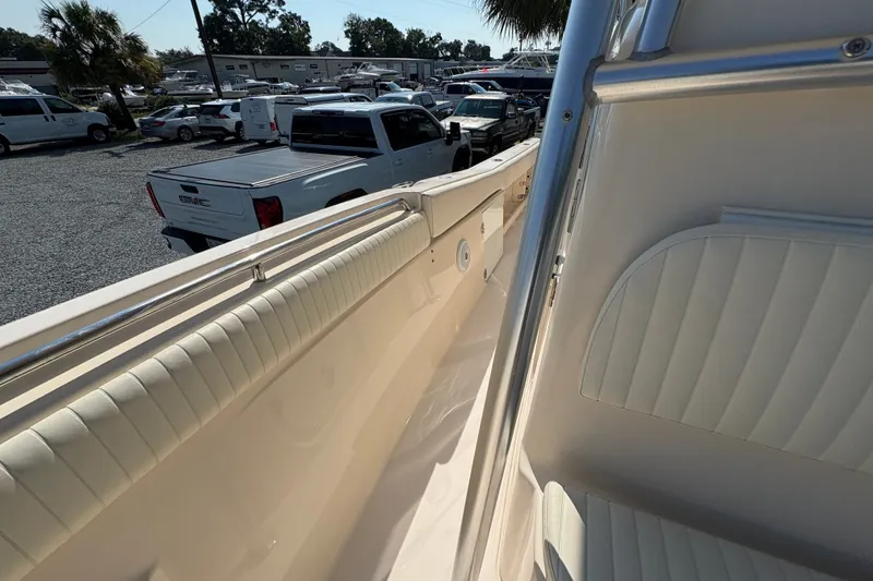 Slide: The Image of 2011 Grady-White Canyon 283 boat interior with white seating and railing, parked vehicles in background. - 12