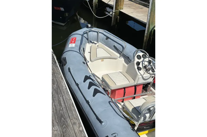 Slide: The Image of 2015 Zodiac Bayrunner 500 inflatable boat docked, featuring steering console and seating. - 2