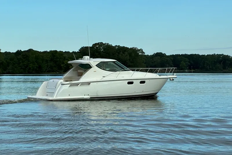 Slide: The Image of A white 2007 Tiara Yachts 3900 Sovran cruising on calm water with a wooded shoreline in the background. - 2