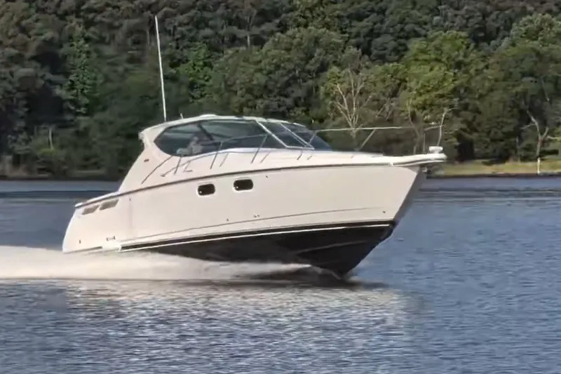 Slide: The Image of 2007 Tiara 3900 Sovran cruising on a serene lake with lush green trees. - 6