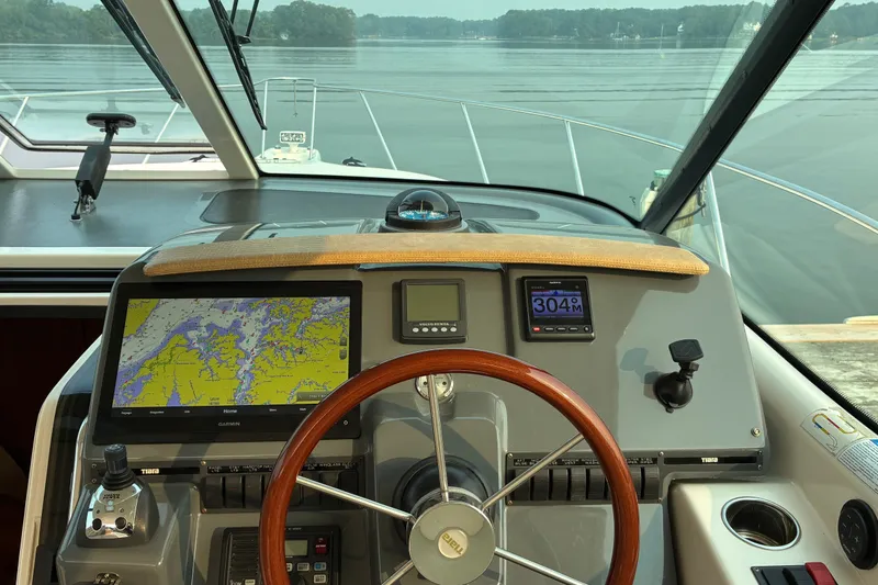 Slide: The Image of 2007 Tiara 3900 Sovran yacht helm with navigation screens and steering wheel on calm waters. - 32