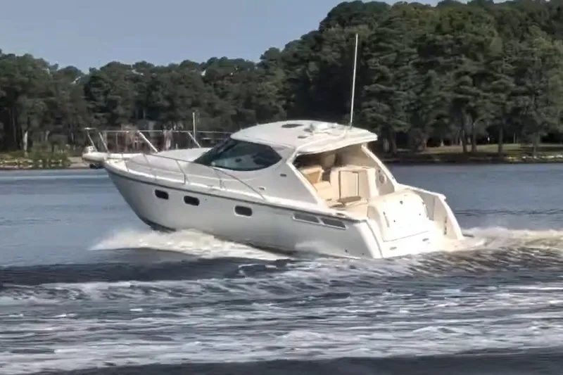 Slide: The Image of 2007 Tiara 3900 Sovran yacht cruising on a serene lake with forested shoreline. - 5