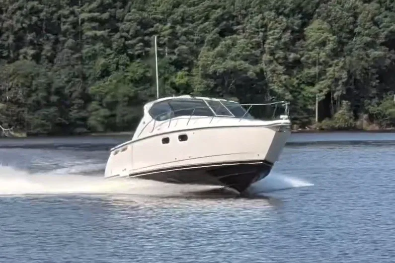 Slide: The Image of 2007 Tiara 3900 Sovran cruising on a serene lake with lush forest backdrop. - 4