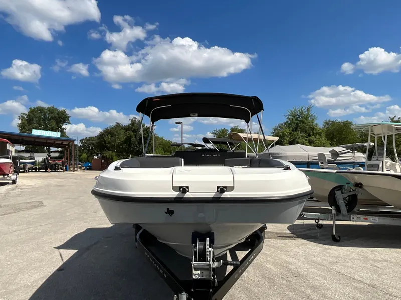 Slide: The Image of A 2021 Bayliner DX 2050 sits on a trailer under a blue sky with clouds. - 2