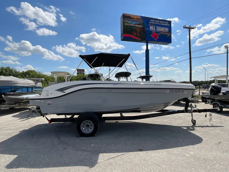 The Image of 2021 Bayliner DX 2050 on a trailer, featuring a black Bimini top, parked outdoors. - 1