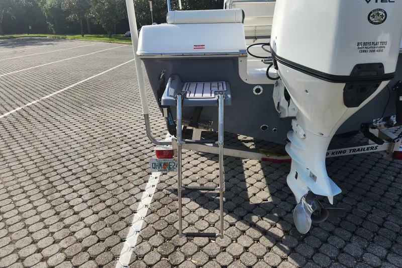 Slide: The Image of 2023 Tidewater 196 CC Adventure boat with ladder and outboard motor in parking lot. - 15