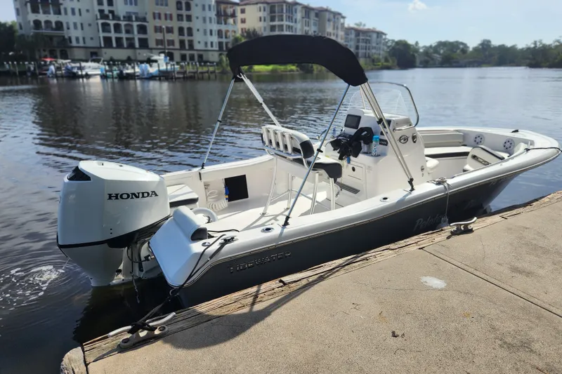 Slide: The Image of 2023 Tidewater 196 CC Adventure boat docked by waterfront buildings. - 2