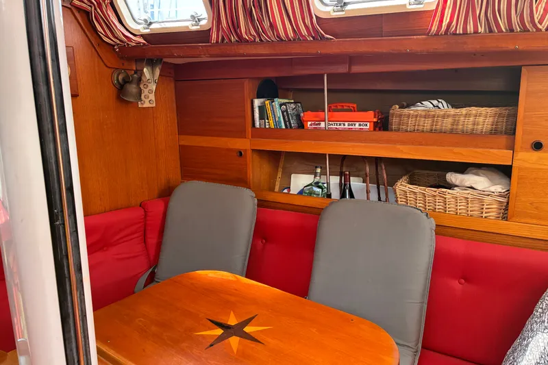 Slide: The Image of Cozy interior of 1989 CAL 39 sailboat with wooden shelves and red seating. - 3