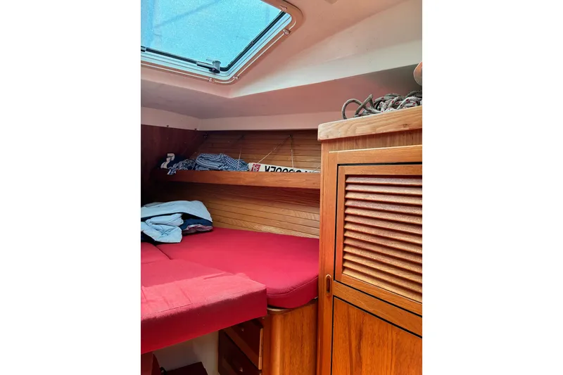 Slide: The Image of Cozy cabin interior of 1989 CAL 39 sailboat with red cushions and wooden storage. - 27
